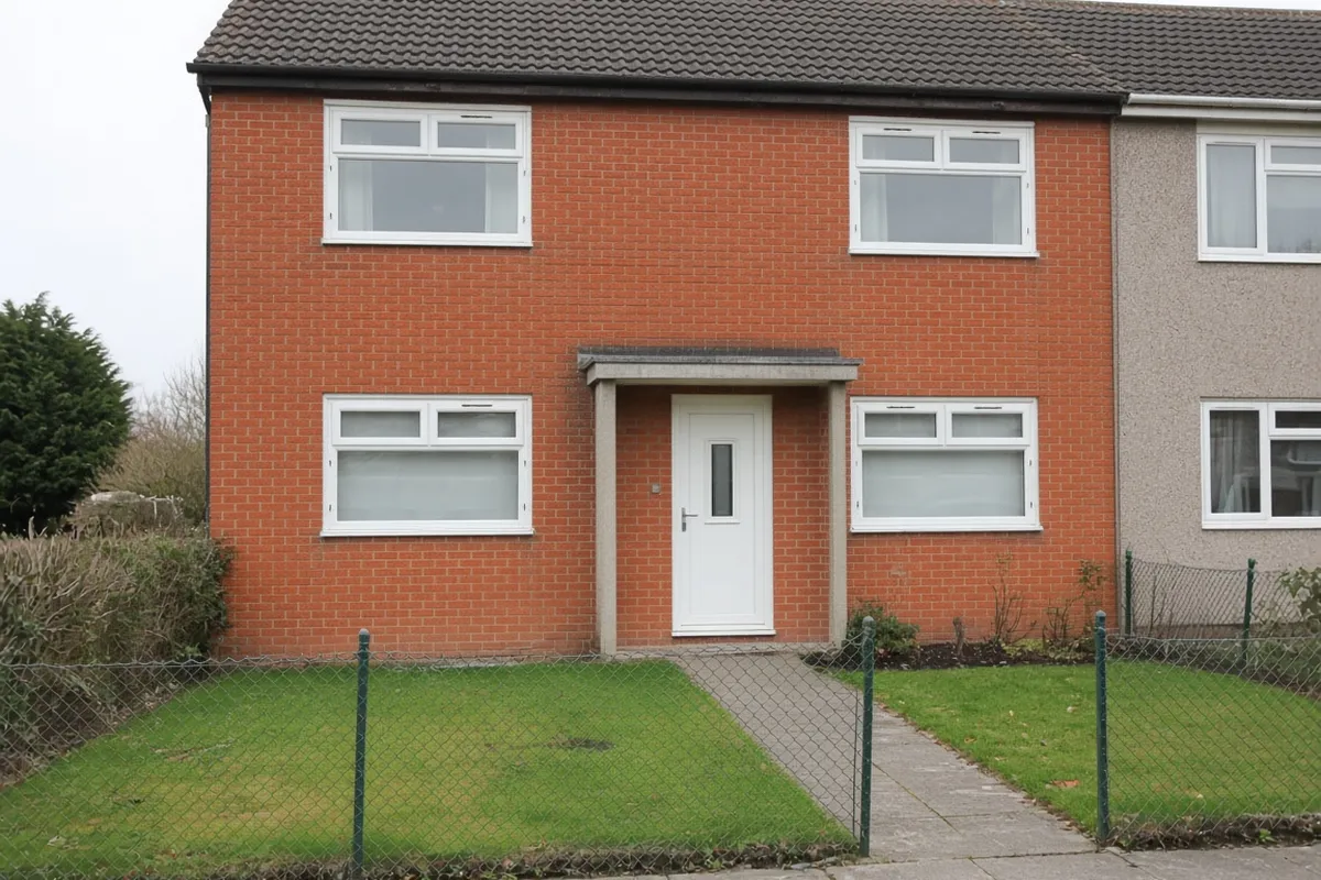 A 1950s brick semi-detached house with white chamfered uPVC casement windows